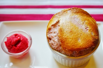 Fresh raspberry souffle in a ramekin with raspberry sorbet