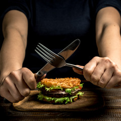 Healthy lifestyle, proper nutrition. Female hands show ban on wholesome rice burger with vegetables, herbs and cutlet on a wooden board