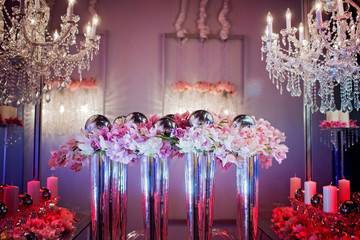 High end wedding tablescape with pillar candles and pink orchids and chandelier