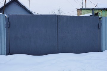gray closed metal gates in snowdrifts of white snow