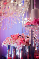 High end wedding tablescape with pillar candles and pink orchids and chandelier