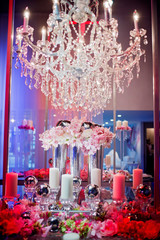 High end wedding tablescape with pillar candles and pink orchids and chandelier