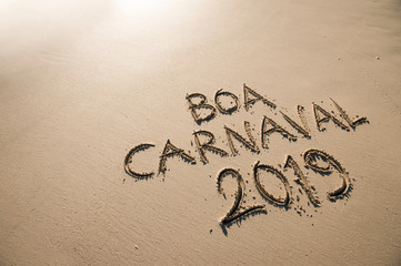 Boa Carnaval 2019 message, Portuguese for Happy Carnival, handwritten on smooth sand beach in Rio de Janeiro, Brazil