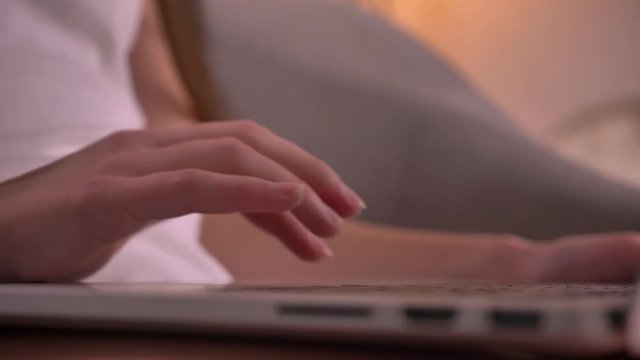 Closeup shoot of female hands typing on the laptop at cozy home indoors. Blurring and refocusing objectives