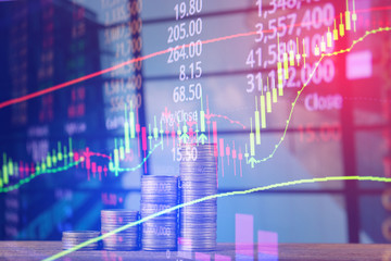 Double exposure of coin stack with stock market screen chart board and candle stick for financial business and investor analysis concept.