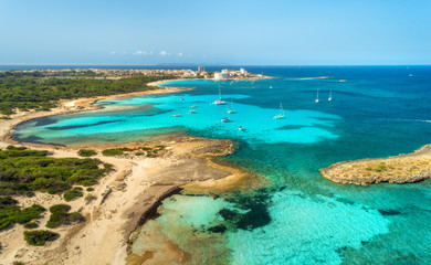 Fototapeta premium Aerial view of beautiful sea with transparent azure water, rocks, sandy beach, green trees, boats and luxury yachts at sunny day in summer. Mallorca, Spain. Colorful seascape. Top view from drone