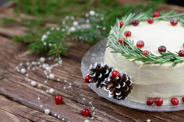 Fototapeta na wymiar Cake with butter cream and rosemary and cranberry decor on a wooden table