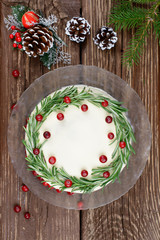  Cake with butter cream and rosemary and cranberry decor on a wooden table