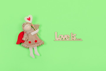 Valentines day pastel minimal creative background. Text Love is and toy angel, cupid, fairy on green background. Valentines day, Love, romance concept