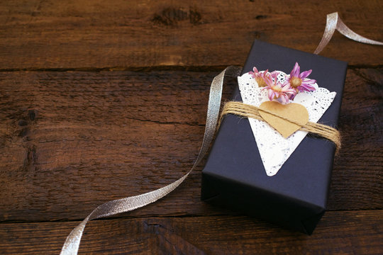 Valentines day, birthday Craft gift box with decor Black paper present box with heart, lace napkin, jute rope on wooden background. Love, romance, handmade concept