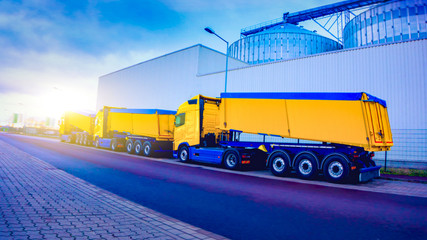 On the road a car for transportation of grain . the yellow truck with the trailer . Agricultural...