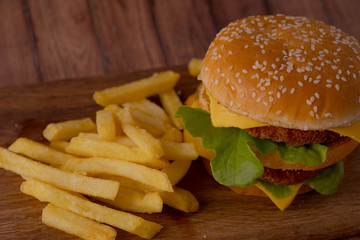 Homemade hamburger on a wooden tray with french fries. Delicious sandwich hamburger with meat or pork ham cheese and fresh vegetable. Hamburger or sandwich is the popular fast food for brunch or lunch