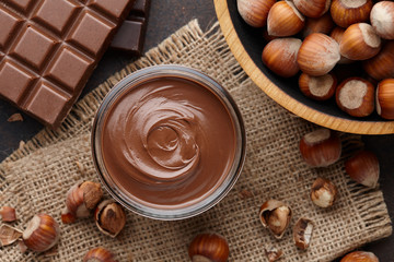Chocolate spread, nuts and chocolate bars on table