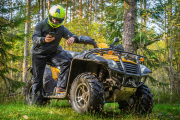 A man travels on ATV. Yellow quad bike. Off-road travel. A man studies the map of the area by...