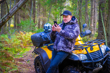 Driver ATV. Traveler in the forest. A man paves the route for travel. Navigation in the forest. Tourist paves the route on the phone. Maps navigation on mobile devices. ATV © Grispb