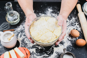 Bakery. Man preparing bread, Easter cake, Easter bread or cross-buns on wooden table in a bakery close up. Man preparing bread dough.