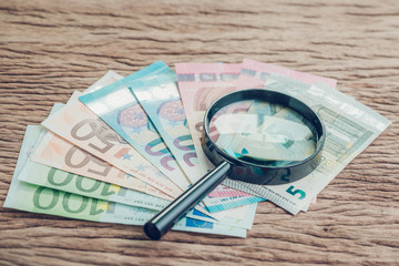 Finance saving, tax, investment or searching for yield concept, magnifier glass on pile of Euro...