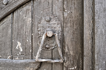 Wrought iron door handle on rough old wooden door made of boards