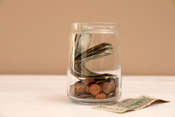 Donation jar with money on table against color background