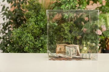 Donation box with money on table against blurred background. Space for text