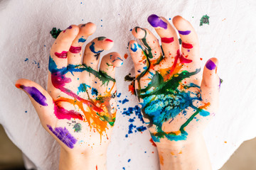 A child's hands are covered in red, pink, yellow, orange, red, blue, green, and purple ink.  Concepts: art, education, play, watercolor, finger painting, mess, creativity, fun, enjoyment