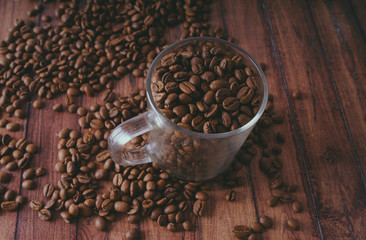 Coffee cup filled with coffee beans over a brown background