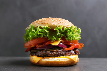 Tasty burger with bacon on table against grey background