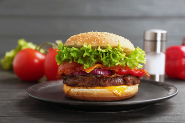Plate with tasty burger on wooden table