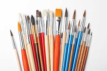 Different paint brushes on white background, top view