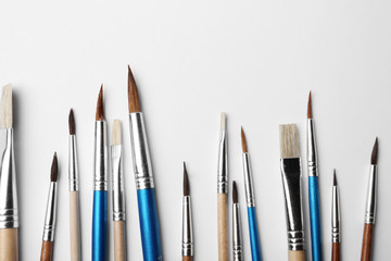 Obraz premium Different paint brushes on white background, top view