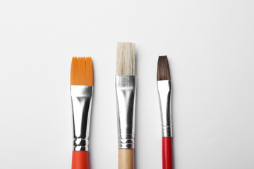 Fototapeta premium Different paint brushes on white background, top view