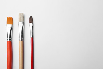 Different paint brushes on white background, top view. Space for text