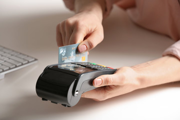 Woman using modern payment terminal at table indoors, closeup