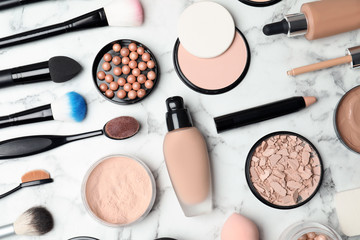 Flat lay composition with skin foundation, powder and beauty accessories on marble background