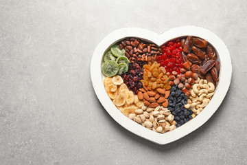 Heart shaped plate with different dried fruits and nuts on table. Space for text