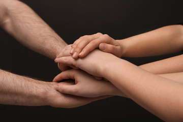 Fototapeta premium Young people putting their hands together on dark background, closeup