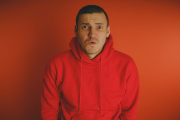 Crazy and charismatic guy posing on an orange background. A man in a red tracksuit.