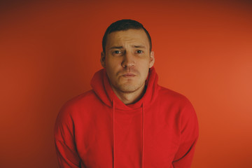 Obraz premium Crazy and charismatic guy posing on an orange background. A man in a red tracksuit.
