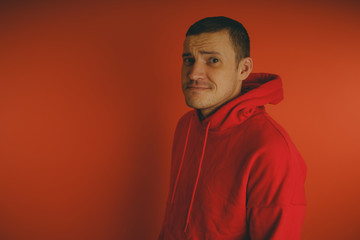 Crazy and charismatic guy posing on an orange background. A man in a red tracksuit.