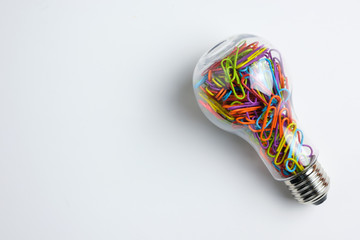 Light bulb filled with multicolor paper clips isolated on white background