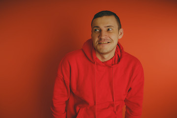 Crazy and charismatic guy posing on an orange background. A man in a red tracksuit.