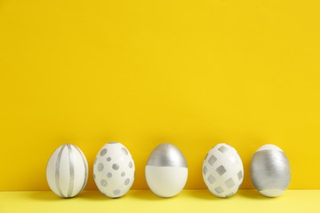 Painted Easter eggs on table against color background. Space for text