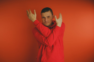 Crazy and charismatic guy posing on an orange background. A man in a red tracksuit.