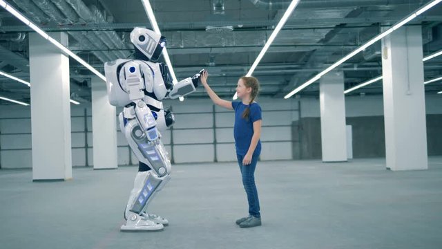 A girl and a robot are touching palms of each other