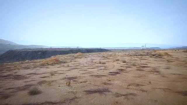 Flying over a girl in a valley next to mines in Greece on a cloudy winter afternoon