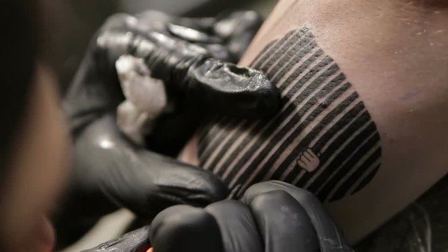 Female tattoo artist finishes the tattoo and corrects the contours, macro