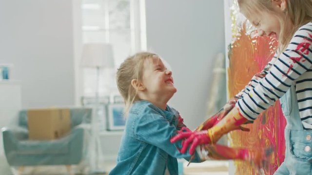 Two Fun Little Sisters Play and Fool Around with Their Hands Dipped in Colorful Paint. They are Happy and Laugh. Sisterhood Goals. Redecoration at Home.