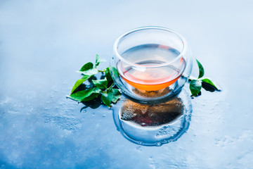 Double wall glass with tea leaves on a light blue background. Hot drink header with copy space.