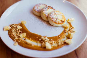 Healthy breakfast. Curd cheese pancakes fried with powdered sugar, caramel and peanuts.
