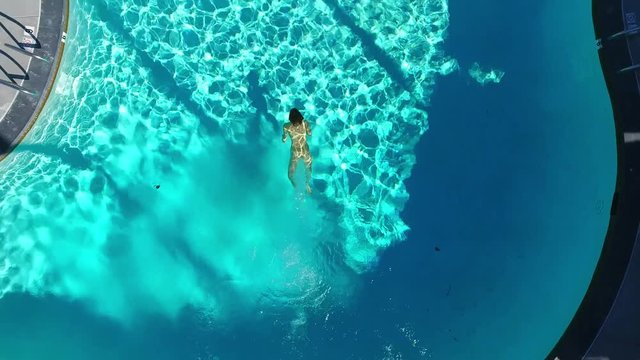 Top view of a naked girl diving in the swimming pool.